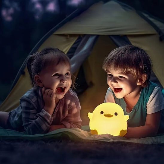 Deux enfants passent une soirée de camping joyeuse avec une veilleuse bébé en forme de poussin.