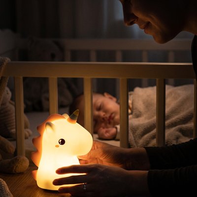 Maman observe la veilleuse licorne avec satisfaction pendant que son bébé dort.