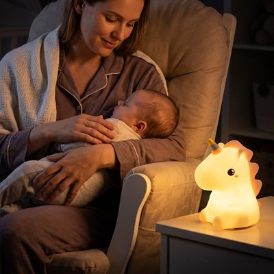 Veilleuse licorne bébé : une lumière douce sur la table de chevet qui accompagne les bras d’une mère berçant son bébé.