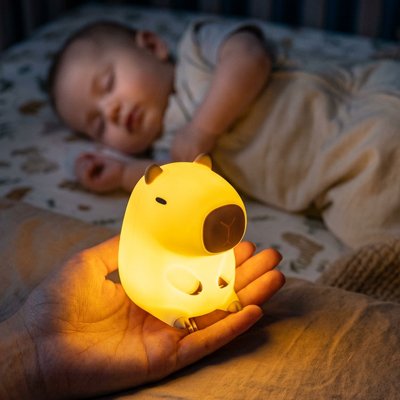 La mère observe son bébé dormir tout en tenant une veilleuse bébé en forme d’animal.