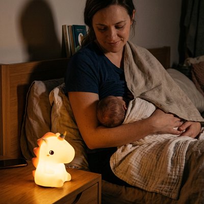 Une veilleuse bébé en forme d’animal éclaire doucement pendant que le bébé dort et que la mère le regarde.